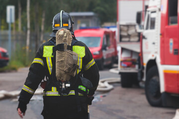 Group of fire men in protective uniform during fire fighting operation in the city streets,...