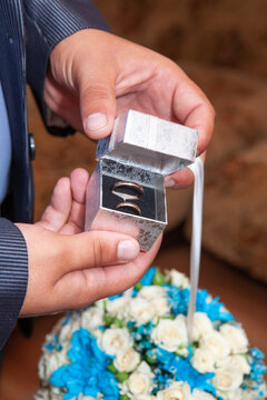 Groom's hands holding a box of wedding rings