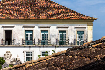 Huge historic house in colonial style with old roof in foreground