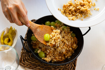 Hands of female cook portioning traditional Aragonese dish Migas del pastor from fried wheat bread...