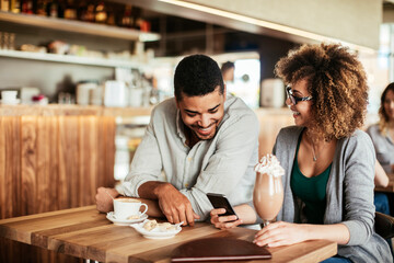 Young African American couple using a smartphone while on a date in a cafe