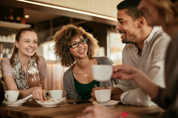 Young and diverse group of people talking and having coffee together in a cafe