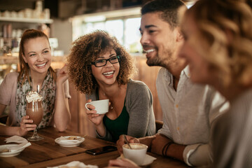 Young and diverse group of people talking and having coffee together in a cafe