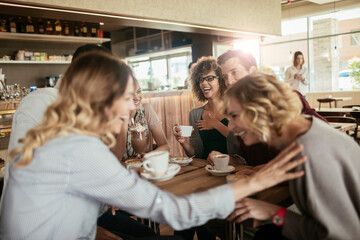 Young and diverse group of people talking and having coffee together in a cafe