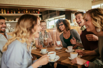 Young and diverse group of friends talking while having coffee together in a cafe