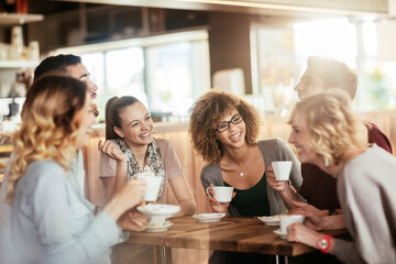 Young and diverse group of people talking and having coffee together in a cafe