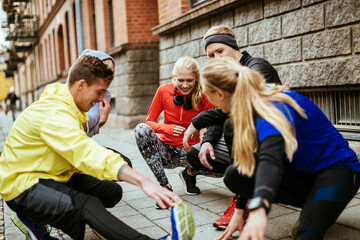Young and diverse group of friends stretching and getting ready to exercise and jog in the city