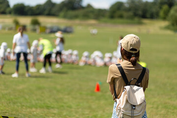 Back of young woman watching kids sport competition