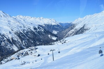 Fototapeta na wymiar Gondola ski lifts in Hochgurgl ski resort, backdropped by the Otztal valley and the snow capped alpine mountains in Tyrol, Austria.