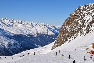 Skiers and snowboarders in Hochgurgl ski resort, backdropped by the Otztal valley and the snow capped alpine mountains in Tyrol, Austria.