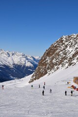 Skiers and snowboarders in Hochgurgl ski resort, backdropped by the Otztal valley and the snow capped alpine mountains in Tyrol, Austria.
