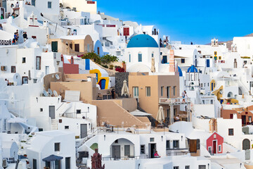 Santorini, Greece - 05 27 2023: Oia caldera's colorful white-washed terraces with blue domes on a...