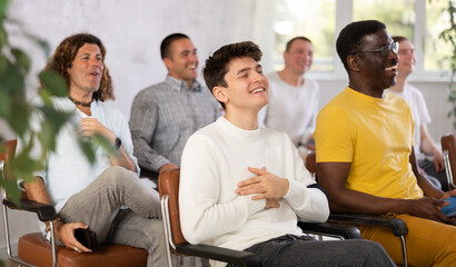 Group of smiling men gays of different nationalities listening to a lecture in the lobby