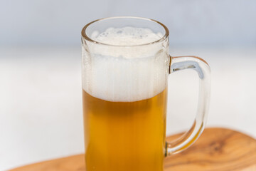 pint glass of hazy pale ale beer on cutting board and white table