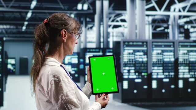 Older admin in servers establishment housing high end processors capable of quickly and efficiently performing complex computations and data analysis, using mockup tablet to do debugging