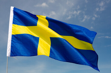 Flag of Sweden flutters in the wind against the blue sky