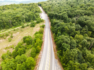 Aerial top view of an empty motorway through a green forest that goes beyond the horizon.