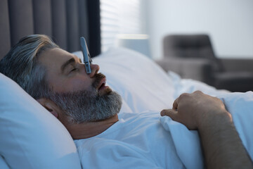 Man sleeping with clothespin on his nose in bed at home. Problem with snoring