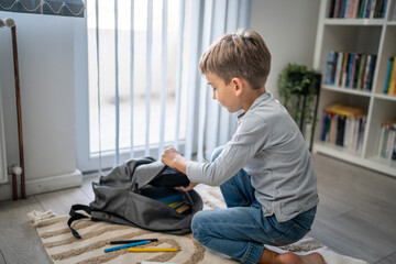 Small boy pupil child prepare his backpack for first day of school