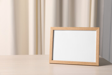 Empty square frame on white wooden table indoors, space for text