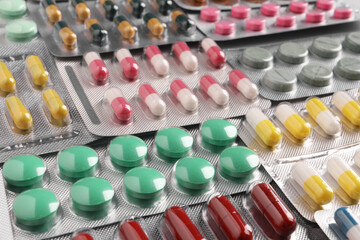 Many blisters with different pills as background, closeup