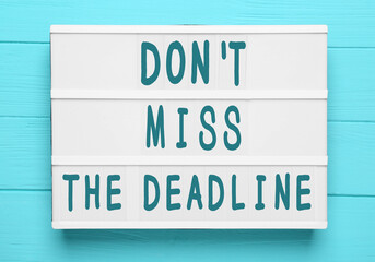 Light box with reminder Don't Miss The Deadline on light blue wooden background