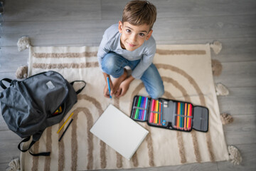 a schoolboy Small caucasian boy play at home draw on the floor
