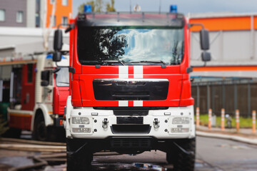 Fire fighting equipment in the city, with red fire engine truck during fire fighting operation in the city streets, vehicle and firefighters extinguish blaze, emergency and rescue service vehicle