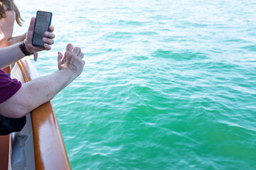 Person holding cell phone leaning on railing of a boat  in Lake Ontario Canada 
