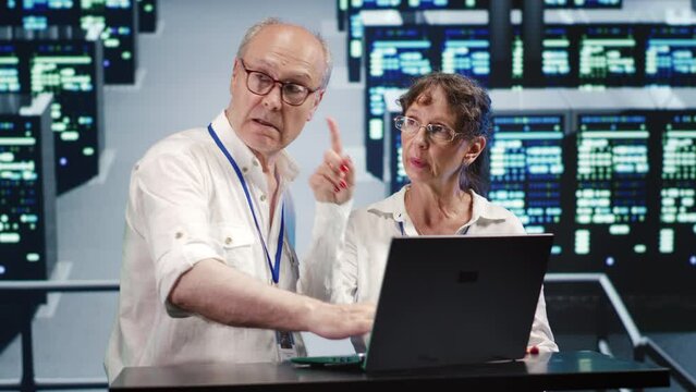 Aged coworkers looking around modern server farm, preparing to start comission on malfunctioning high tech workspace hardware clusters in order to ensure proper operations