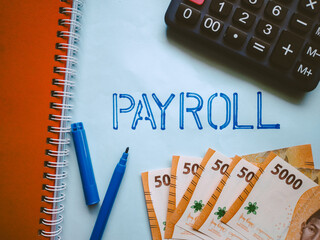 PAYROLL word on blue paper background. Payroll summary report or calculating annual tax and human...