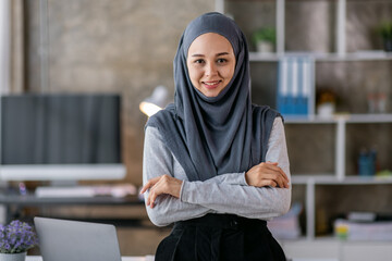 Happy arab Muslim woman in hijab freelancer in the office, empty space.