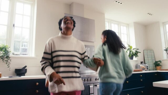 Mature Mother With Teenage Daughter At Home In Kitchen Having Fun Dancing Together  - Shot In Slow Motion