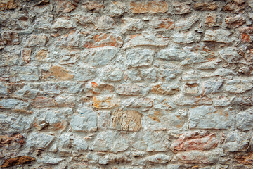 The background of an old brick wall covered with white plaster close up. Texture of white orange brick, light brick background