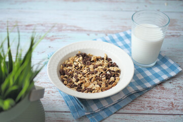 granola Musli in a bowl and glass of milk on table 