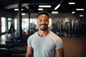 Smiling portrait of a happy young male african american fitness instructor in an indoor gym
