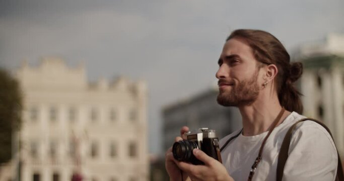 Smiling male tourist admiring sightseeing and taking photos on retro camera