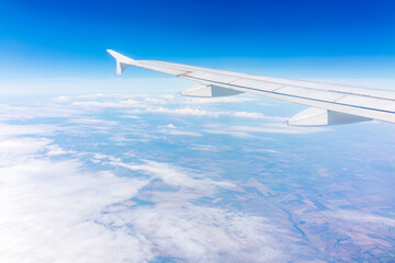 Fototapeta premium View from the airplane window at a beautiful cloudy sky and the airplane wing