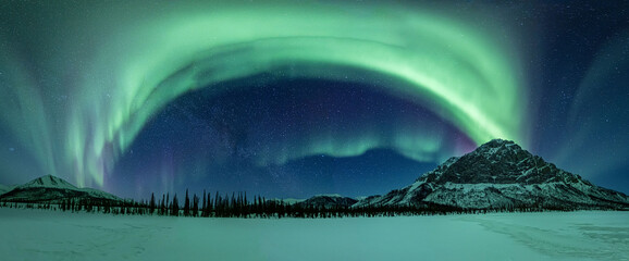 A panorama of the aurora borealis or northern lights over the Brooks Range of northern Alaska, USA. 