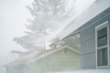 strong wind blowing snow off the roof in blizzard