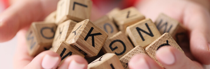 Woman hands hold heap of wooden cubes with letters close up. - obrazy, fototapety, plakaty