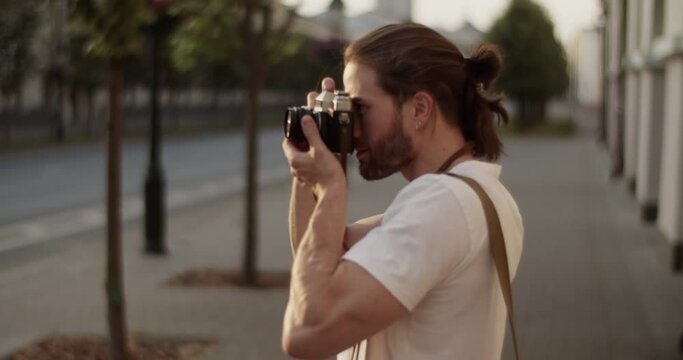 Male photographer taking photos of town on vintage camera