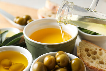 Olive oil, olives and slice of bread on white background, close up