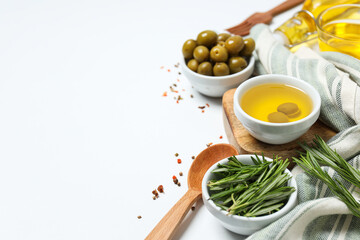 Olive branches, oil and olives in bowls, towel on white background, space for text