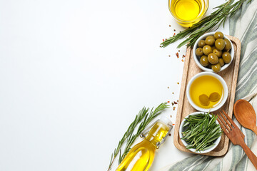 Olive branches, oil and olives in bowls, towel on white background, space for text
