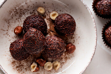 Brigadeiro and hazelnuts in bowl on white background, top view