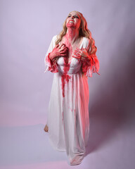  Full length portrait of  scary vampire zombie bride, wearing elegant halloween fantasy costume  dress with bloody red paint splatter. standing walking pose. Isolated on white studio background 