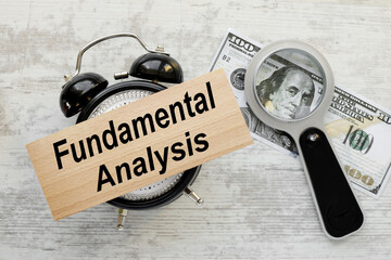 Fundamental Analysis.table clock gray background.text on wooden block. magnifying glass on a bill...