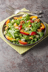 Summer salad of fresh plums, arugula, Gorgonzola cheese and walnuts close-up in a plate on the table. Vertical