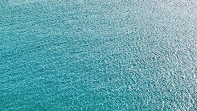 Blue sea water texture airdrone view. Blue surface of the lagoon. Vast blue ocean background with moderate waves looking straight down. Tropical landscape. Tourism.